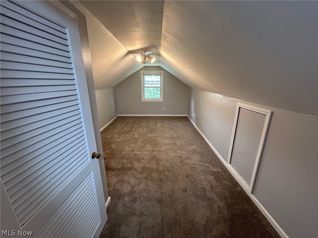 bonus room featuring lofted ceiling and dark colored carpet