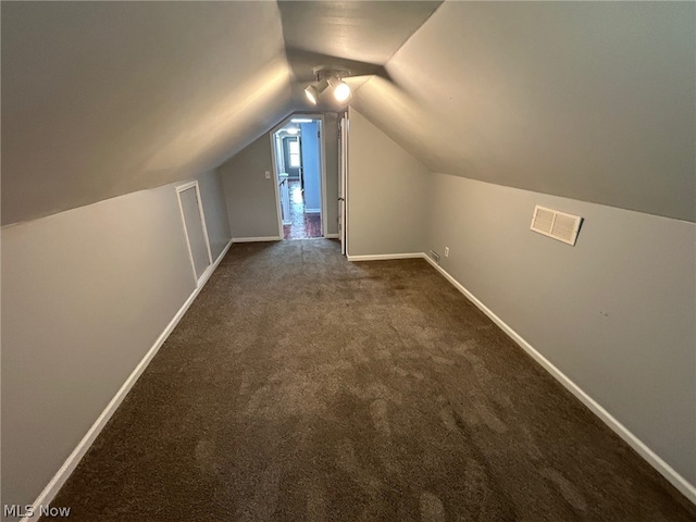 additional living space featuring dark colored carpet and vaulted ceiling