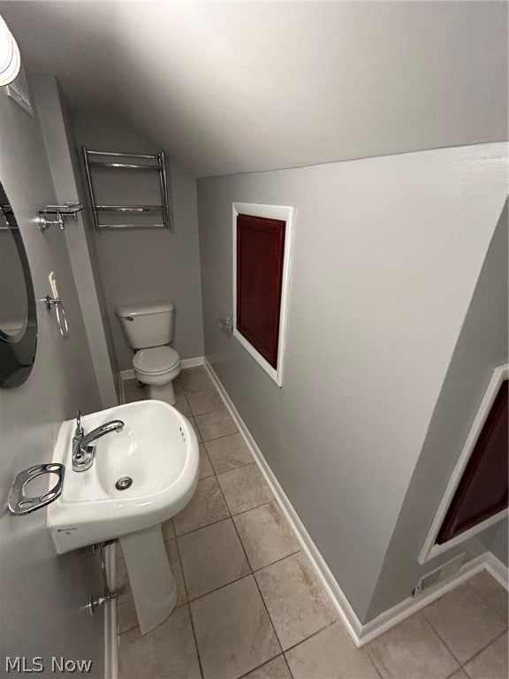 bathroom with lofted ceiling, tile patterned floors, and toilet