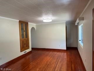 spare room featuring crown molding and dark wood-type flooring