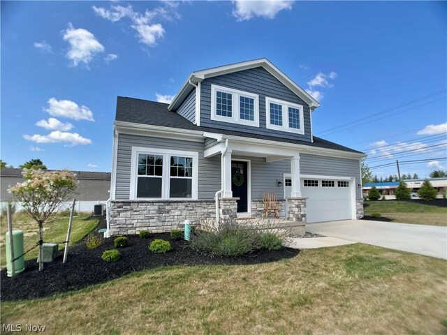 craftsman-style home with a garage, a porch, cooling unit, and a front yard