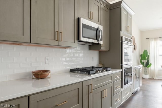 kitchen featuring stainless steel appliances, tasteful backsplash, gray cabinets, and hardwood / wood-style floors