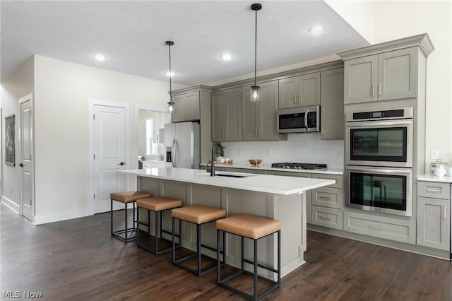 kitchen with sink, a center island with sink, appliances with stainless steel finishes, dark hardwood / wood-style flooring, and gray cabinets