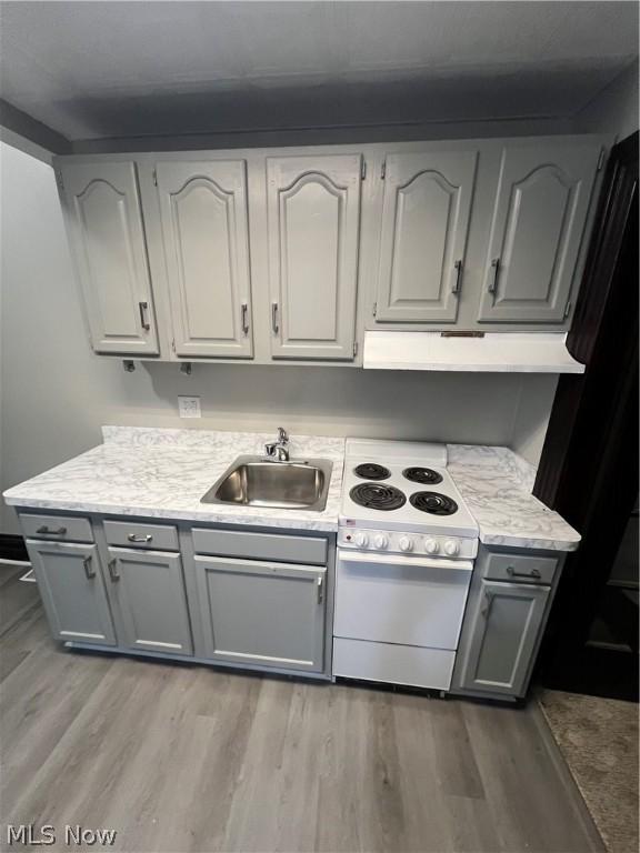 kitchen featuring sink, light hardwood / wood-style flooring, gray cabinets, white electric range oven, and black fridge