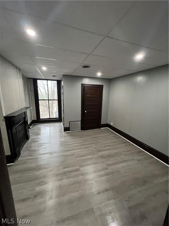 basement featuring light wood-type flooring and a drop ceiling