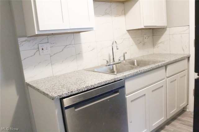 kitchen with light hardwood / wood-style floors, stainless steel dishwasher, white cabinetry, and backsplash