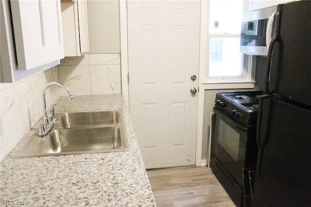 kitchen with black appliances, sink, backsplash, light wood-type flooring, and white cabinetry