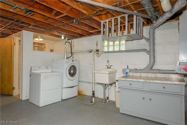 clothes washing area featuring washer and clothes dryer, sink, and cabinets