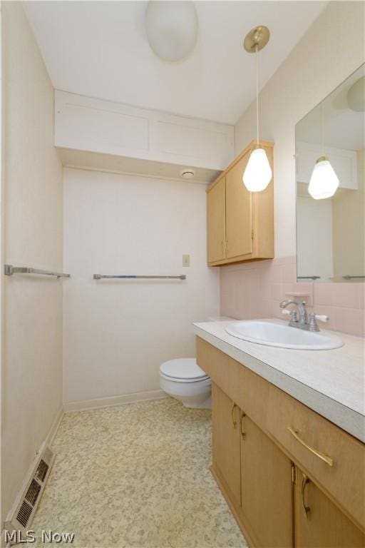 bathroom with vanity, toilet, and decorative backsplash