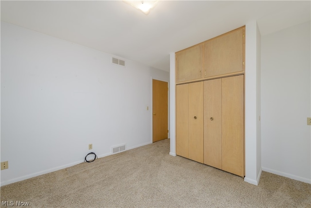 unfurnished bedroom featuring light carpet and a closet