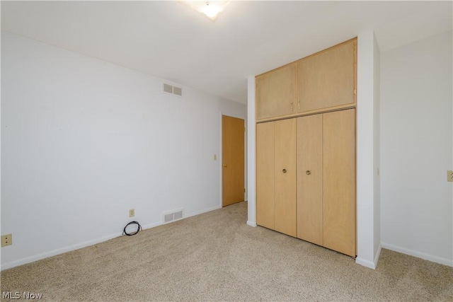 unfurnished bedroom with light colored carpet and a closet