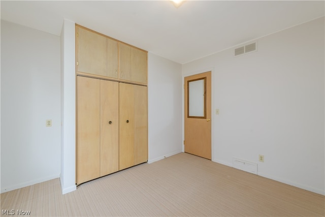 unfurnished bedroom with light carpet and a closet