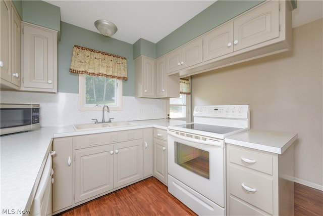 kitchen with sink, electric stove, hardwood / wood-style flooring, and white cabinetry