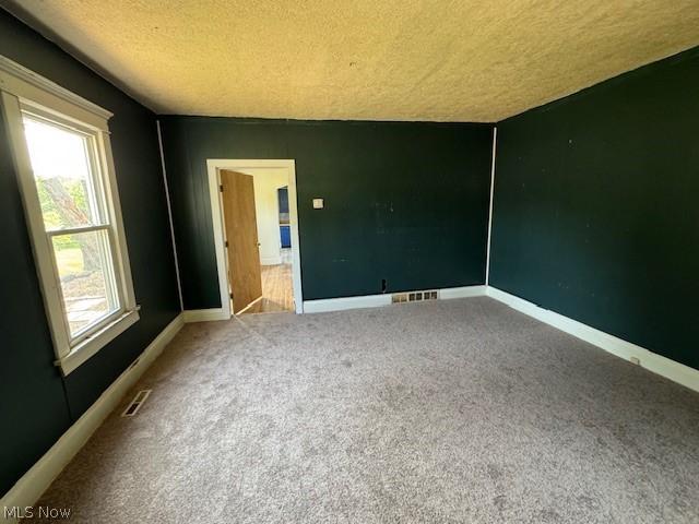 carpeted empty room with a textured ceiling