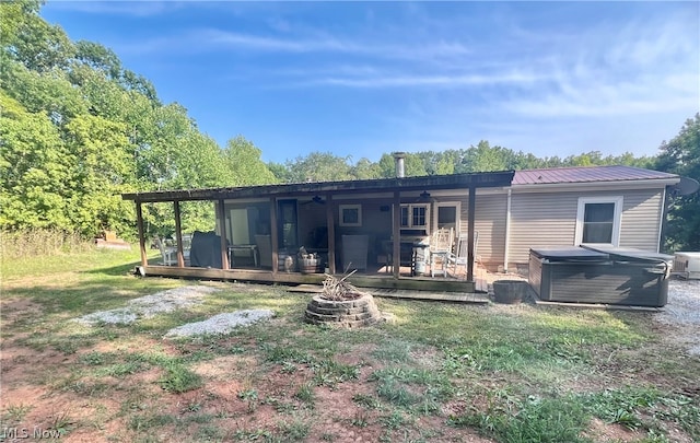 rear view of property featuring a wooden deck, a yard, and a hot tub