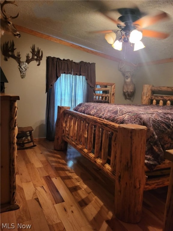 bedroom with hardwood / wood-style floors, ceiling fan, ornamental molding, and a textured ceiling