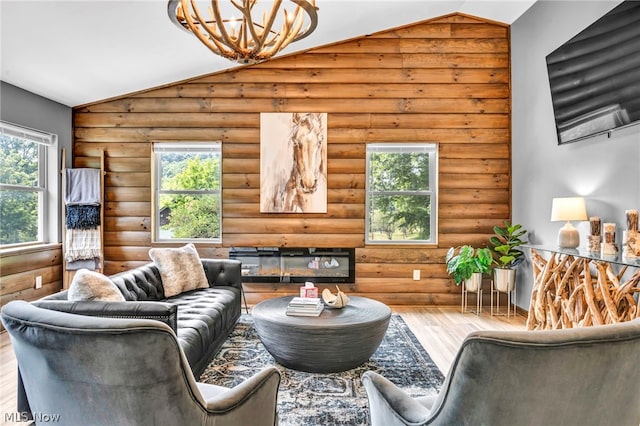 living room featuring a healthy amount of sunlight, vaulted ceiling, and log walls