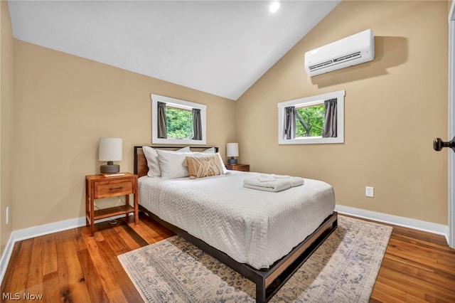 bedroom with a wall mounted air conditioner, lofted ceiling, and hardwood / wood-style flooring