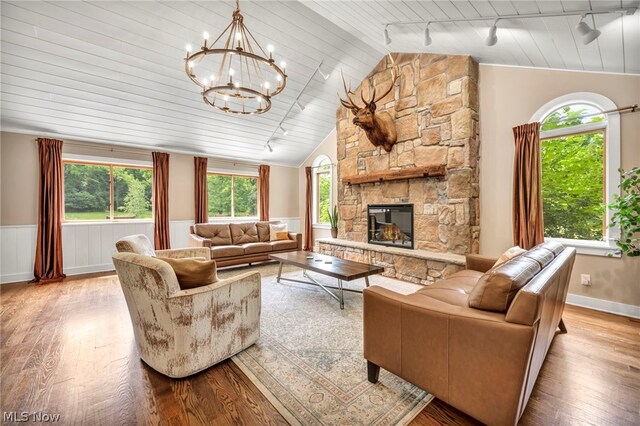 living room featuring a stone fireplace, track lighting, light hardwood / wood-style floors, and plenty of natural light