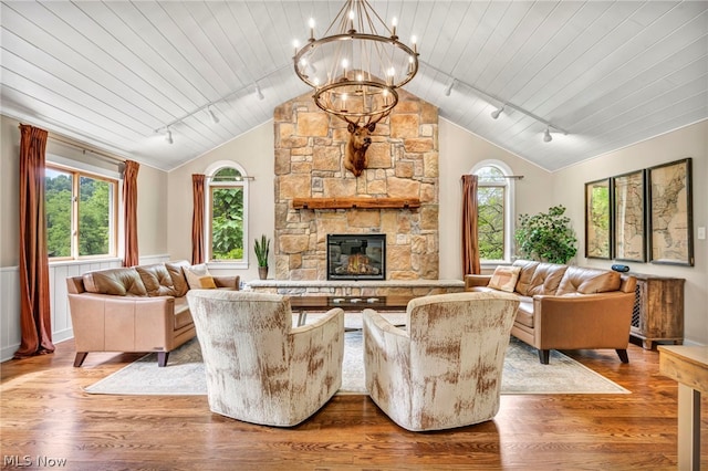 living room with a fireplace, vaulted ceiling, rail lighting, and light wood-type flooring