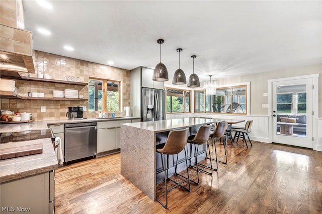 kitchen with light hardwood / wood-style floors, hanging light fixtures, plenty of natural light, and stainless steel appliances