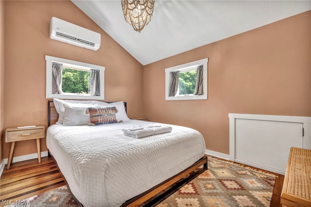 bedroom with a wall unit AC, multiple windows, lofted ceiling, and hardwood / wood-style floors