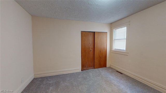 unfurnished bedroom featuring a closet, carpet, and a textured ceiling