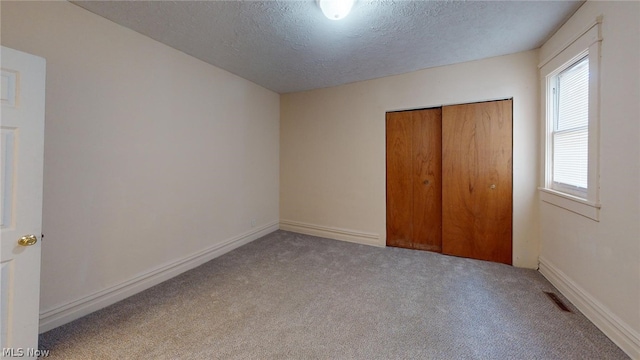 unfurnished bedroom featuring light carpet, a closet, and a textured ceiling