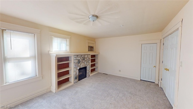 unfurnished living room featuring light colored carpet and a stone fireplace