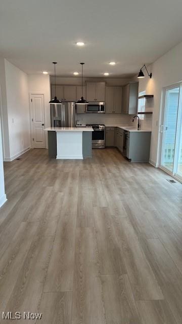 kitchen with gray cabinetry, appliances with stainless steel finishes, light countertops, and decorative light fixtures