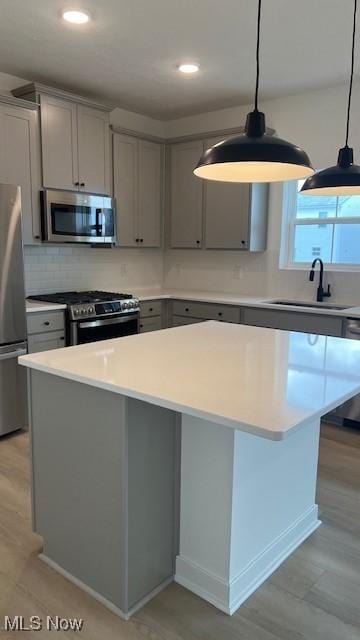 kitchen with light countertops, appliances with stainless steel finishes, a sink, and pendant lighting