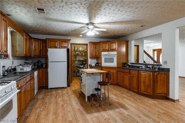 kitchen with wood counters, sink, white appliances, light hardwood / wood-style floors, and a textured ceiling