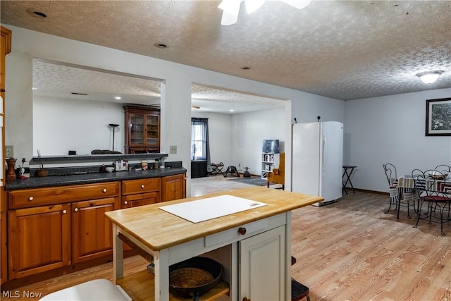 kitchen featuring white refrigerator, a textured ceiling, and light hardwood / wood-style floors