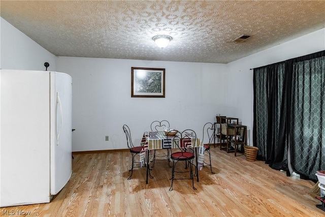 dining room featuring a textured ceiling and light hardwood / wood-style flooring