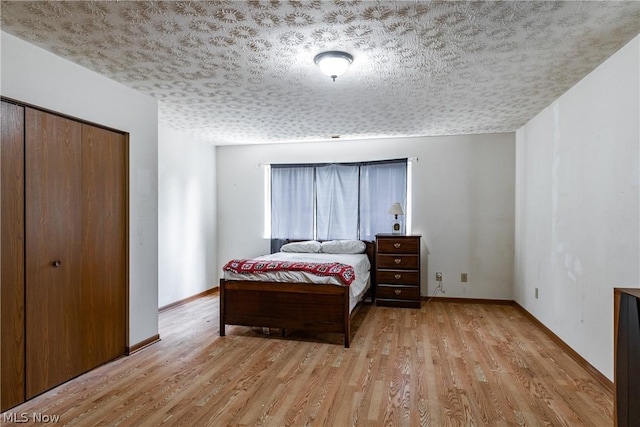 bedroom featuring light hardwood / wood-style floors, a closet, and a textured ceiling