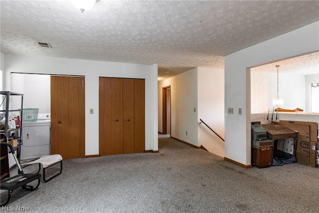 carpeted bedroom with multiple closets, washer / dryer, and a textured ceiling