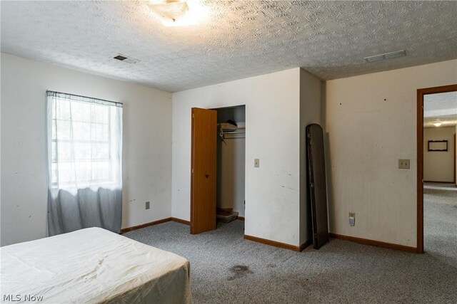 carpeted bedroom with a closet and a textured ceiling