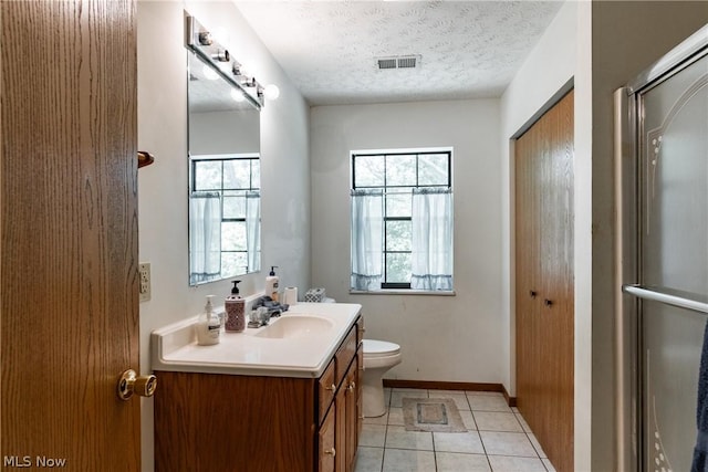 bathroom featuring tile patterned flooring, vanity, an enclosed shower, toilet, and a textured ceiling