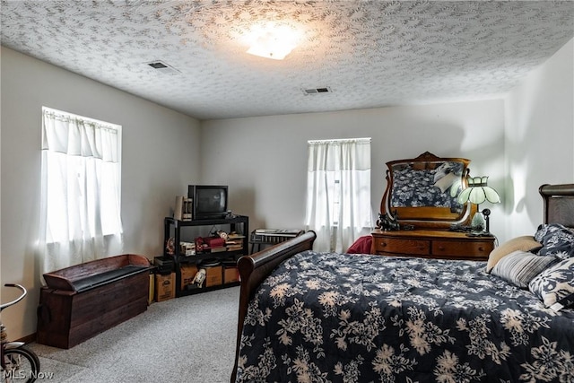 bedroom featuring light colored carpet, multiple windows, and a textured ceiling