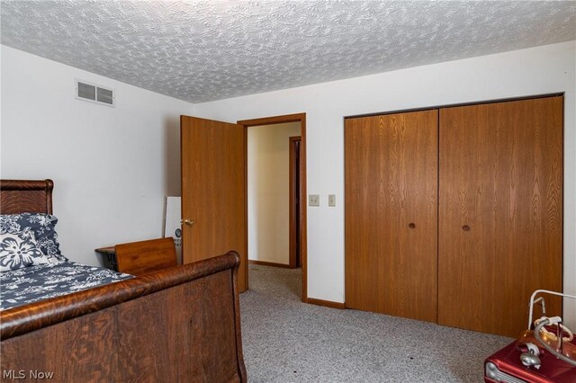 bedroom featuring a closet, light carpet, and a textured ceiling