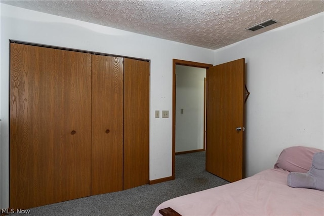 carpeted bedroom with a textured ceiling and a closet