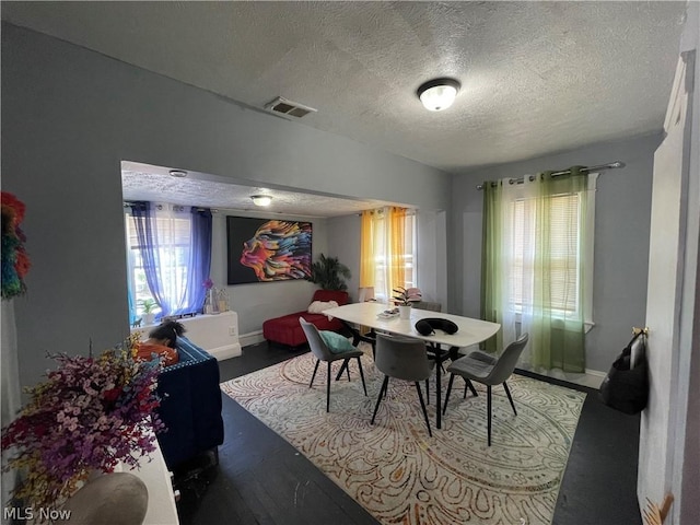 dining room with dark hardwood / wood-style floors and a textured ceiling