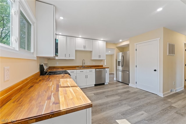 kitchen with wood counters, sink, white cabinetry, light hardwood / wood-style flooring, and appliances with stainless steel finishes