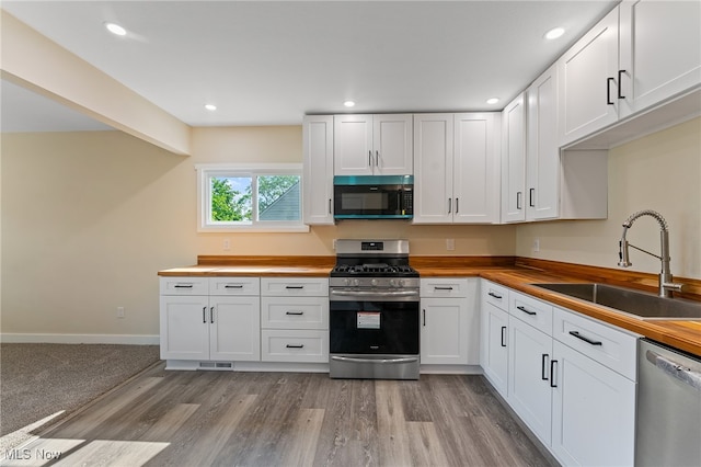 kitchen featuring white cabinetry, appliances with stainless steel finishes, sink, and wooden counters