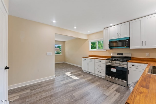 kitchen featuring light hardwood / wood-style floors, stainless steel gas range oven, butcher block countertops, and white cabinetry