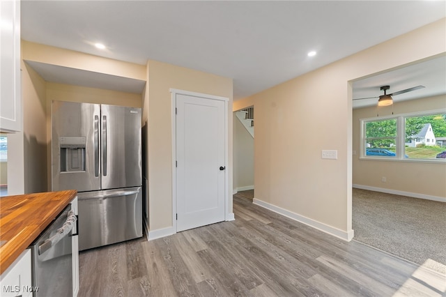 kitchen with ceiling fan, stainless steel appliances, light wood-type flooring, and wood counters