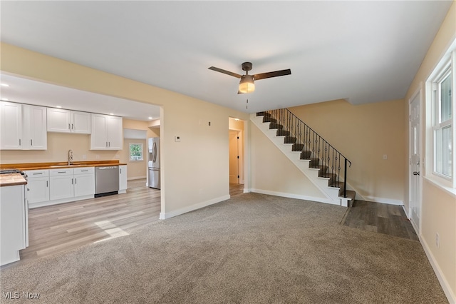 unfurnished living room featuring light hardwood / wood-style floors, ceiling fan, and sink