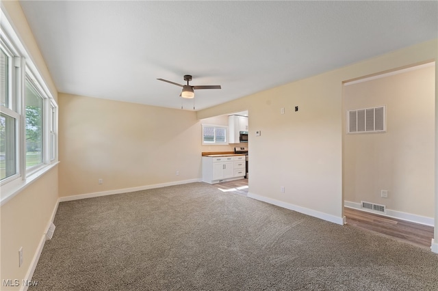 unfurnished living room with carpet and ceiling fan