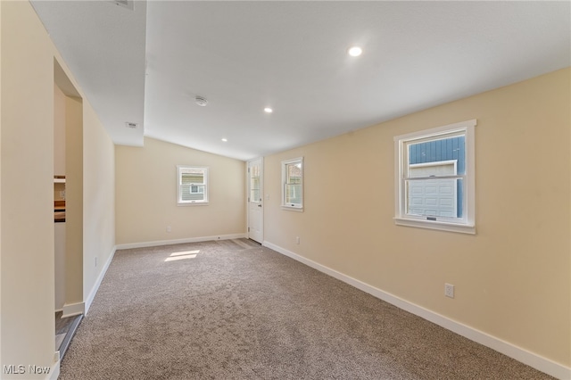 carpeted spare room featuring lofted ceiling