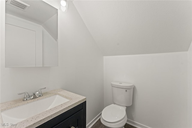 bathroom featuring vanity, toilet, and vaulted ceiling